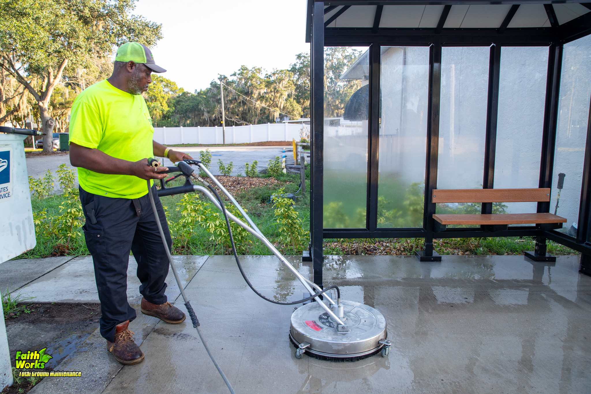 Faithworks technician pressure washing a bus stop